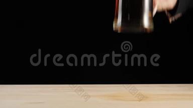 新鲜啤酒。 手把美味的工艺啤酒放进啤酒杯里，放在黑色背景的木桌上。 带水的冷鲜啤酒